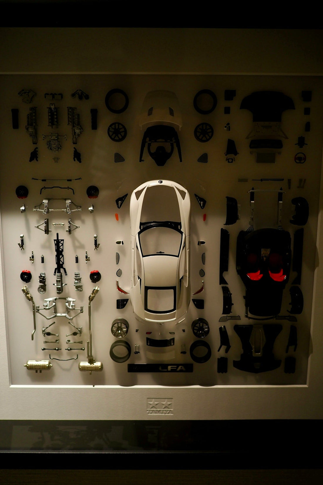 Disassembled supercar model kit with body panels, wheels, and car parts laid out neatly.