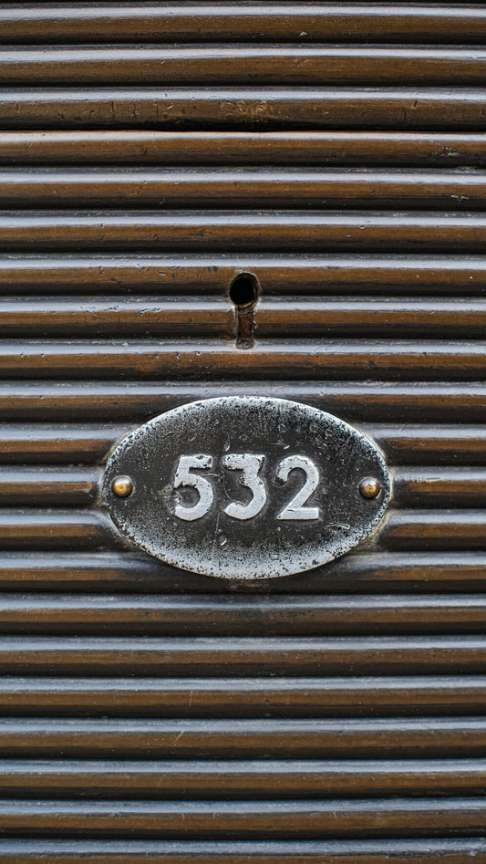 Close-up of vintage metal locker with keyhole and number 532 on ribbed brown surface