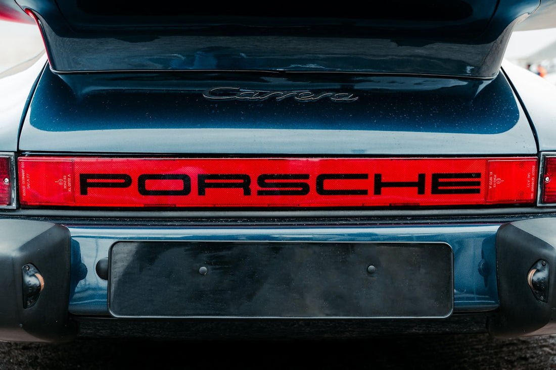 Close-up of a Porsche Carrera rear with red taillight and Porsche logo, luxury sports car