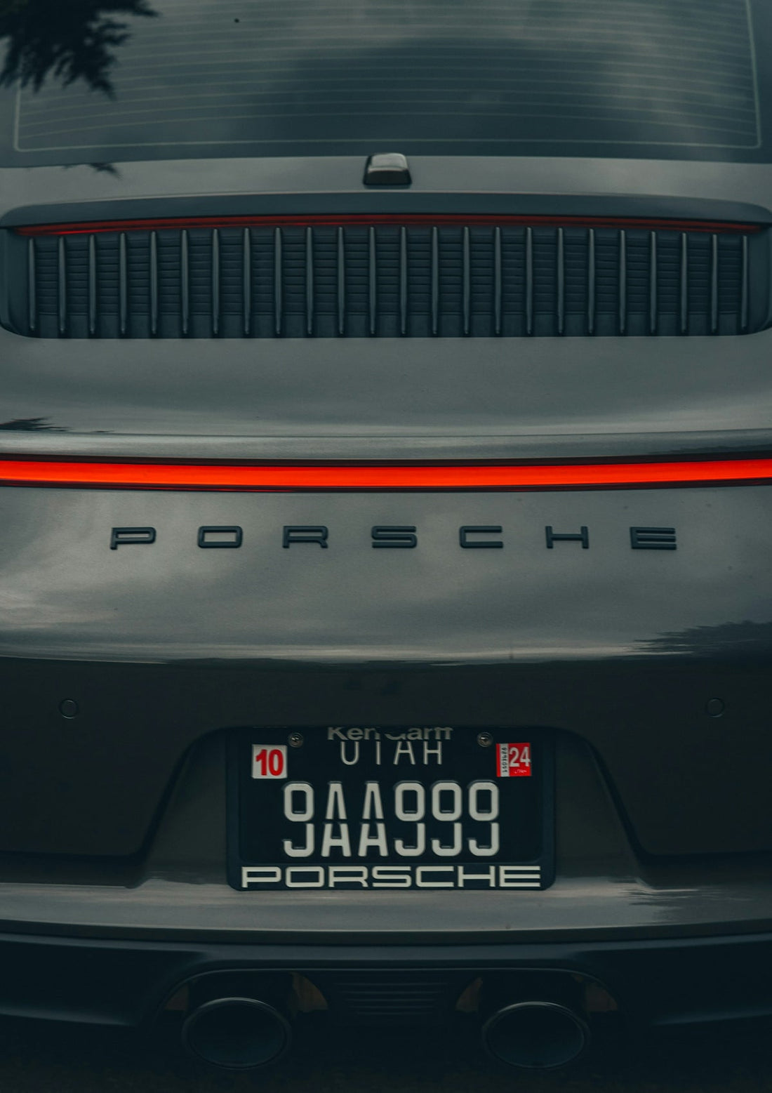 Rear closeup of a gray Porsche sports car with Utah license plate and red tail light.