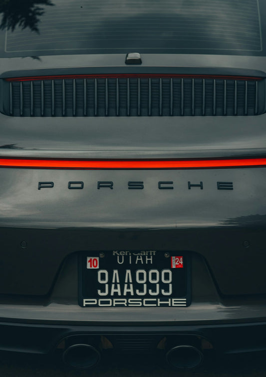 Rear closeup of a gray Porsche sports car with Utah license plate and red tail light.