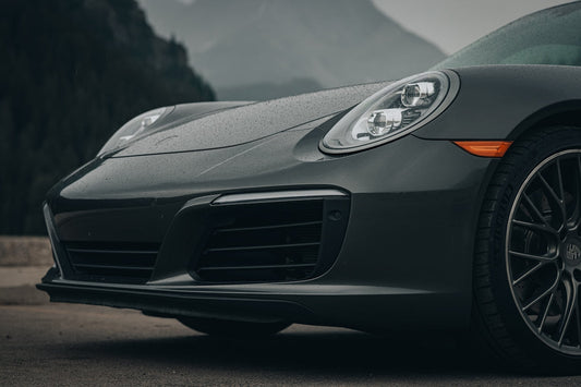 Close-up of a luxury sports car front end with sleek headlight and alloy wheel, outdoors