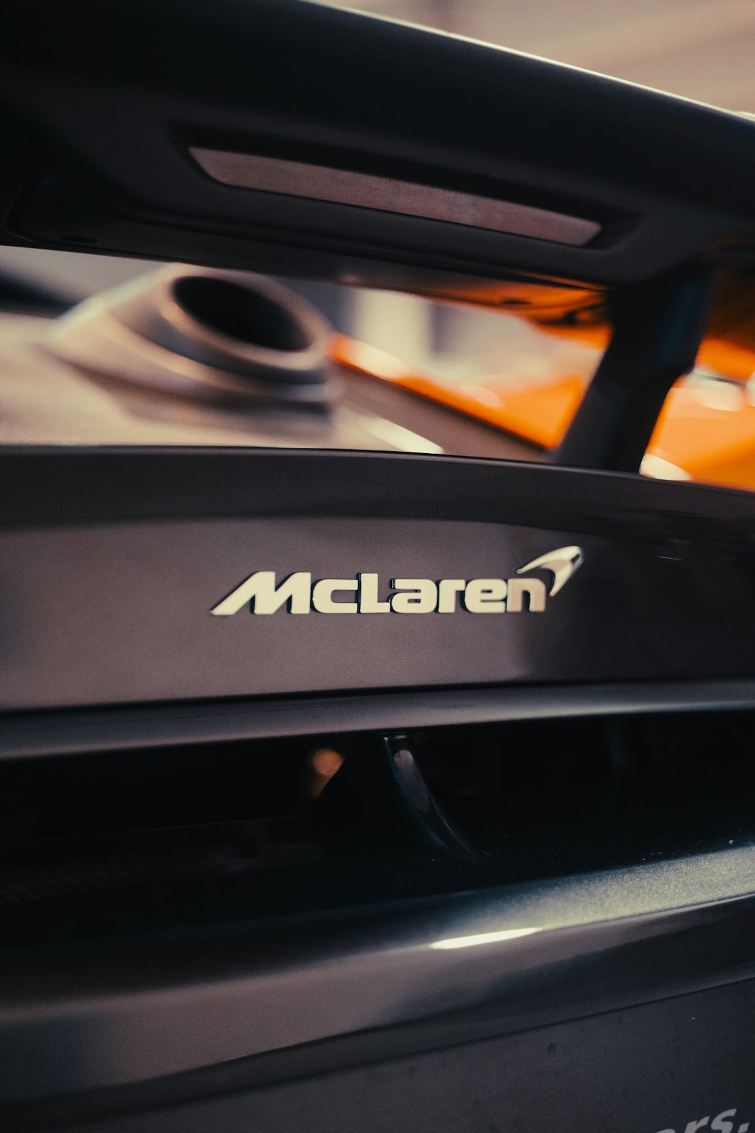 Close-up of McLaren supercar rear wing badge, luxury sports car detail