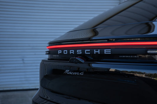 Close-up of black Porsche Macan 4 rear with LED tail light and reflective paint.