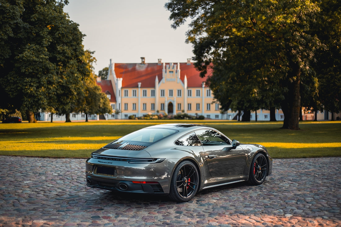 A gray porsche parked in front of a castle.