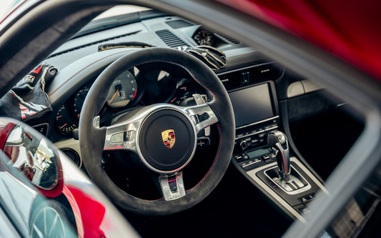 Interior shot of a porsche with steering wheel.