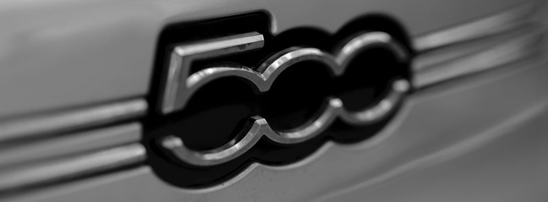 Close-up of Fiat 500 car emblem on a silver vehicle, automotive badge detail