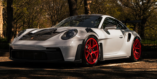 A white porsche with red wheels is parked.