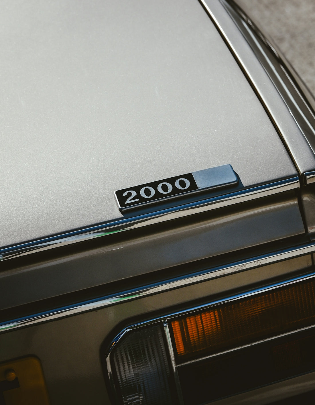 A silver car featuring a 2000 emblem.