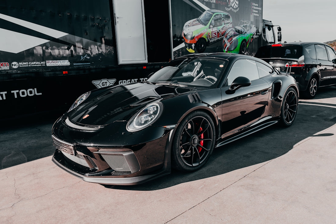 A black porsche gt3 stands in front of a trailer.