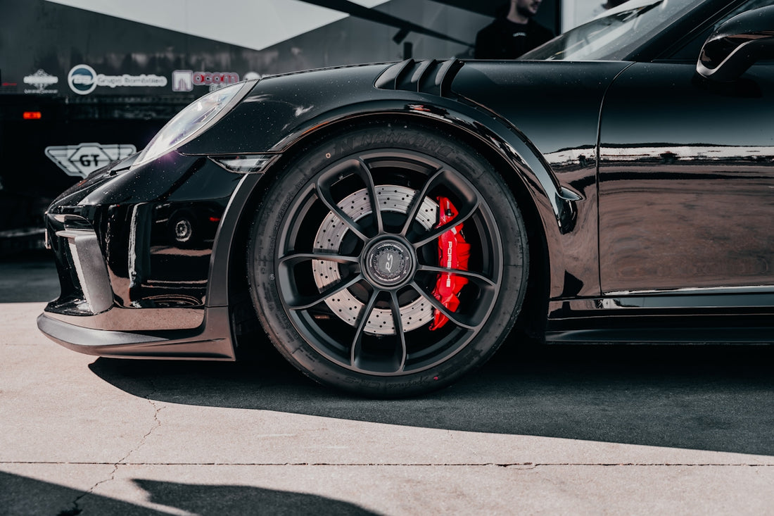 A black porsche car featuring red brake calipers.
