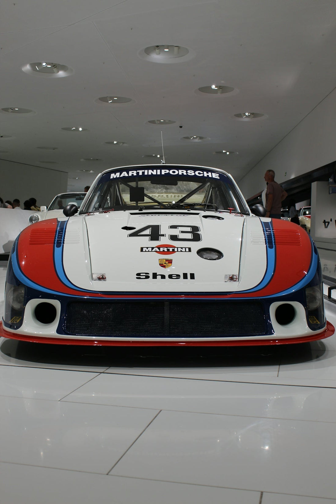 Front view of a classic Martini Porsche race car with number 43 in a showroom