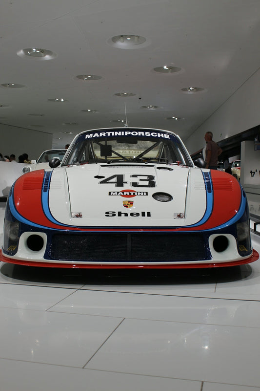 Front view of a classic Martini Porsche race car with number 43 in a showroom
