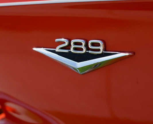 Chrome 289 emblem on red classic car fender, vintage muscle car detail