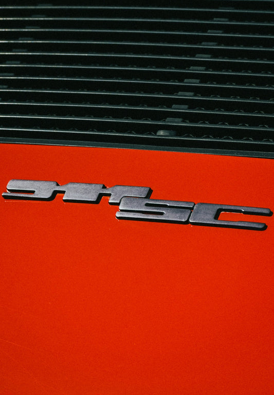 Close-up of orange Ferrari 355 GTS badge and rear air vents, exotic car detail