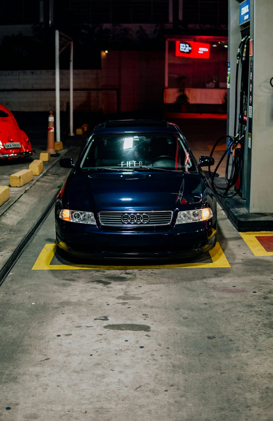 A dark blue audi at a gas station.