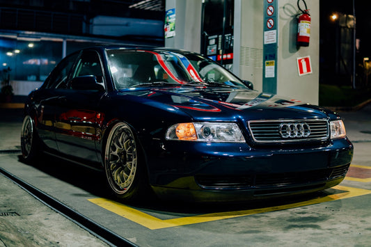 Dark blue Audi sedan with aftermarket wheels parked at night at a gas station