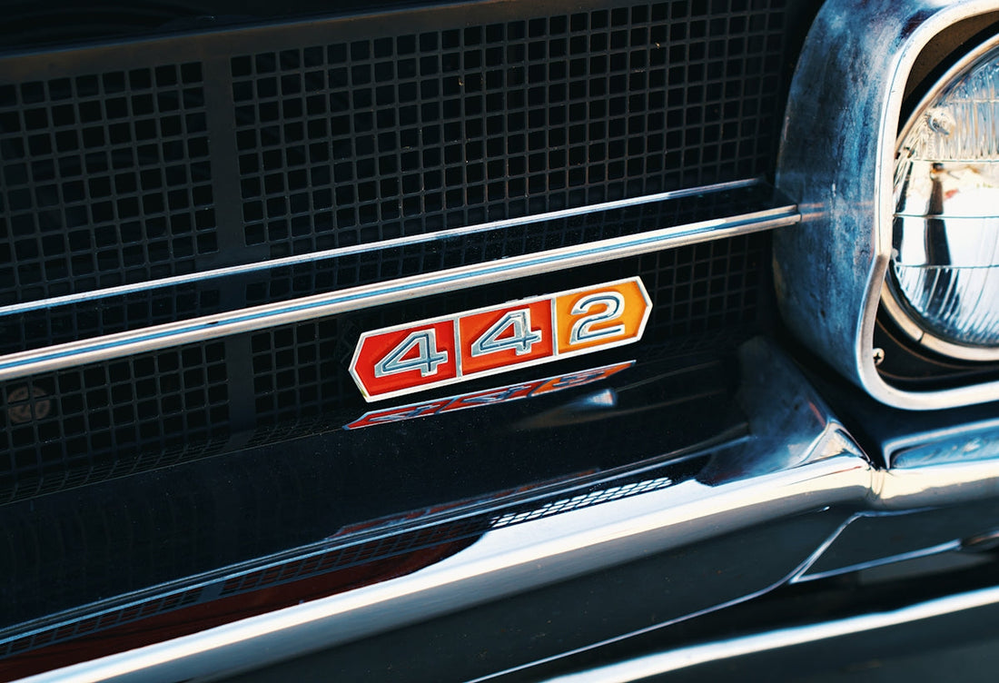 Close-up of a classic car grille with a red and orange 442 emblem and chrome trim