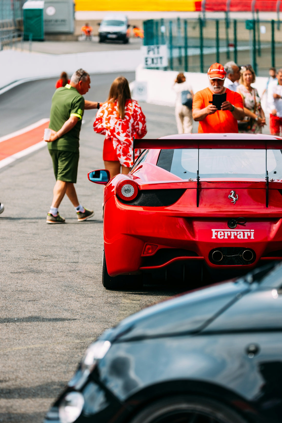 People admire a red ferrari sports car on the track.
