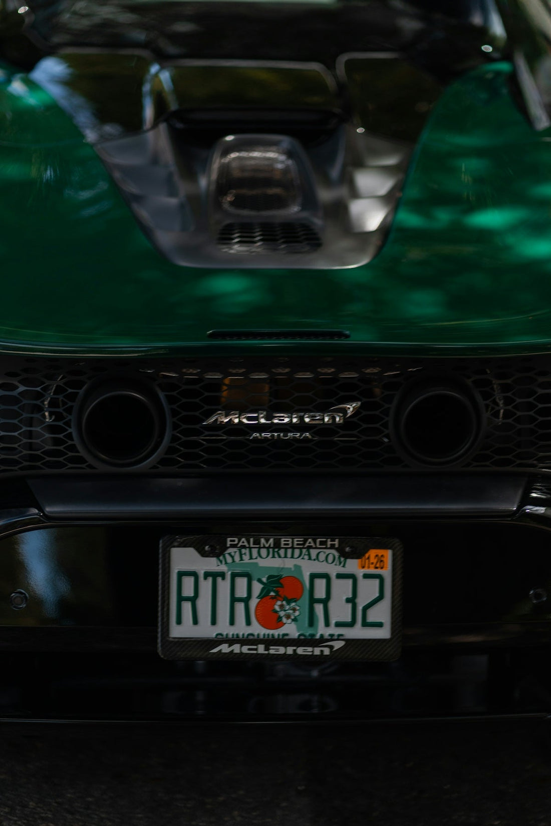 Rear view of green McLaren Artura supercar with visible exhaust and Florida license plate.