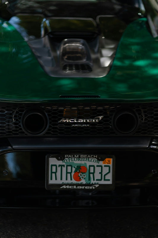 Rear view of green McLaren Artura supercar with visible exhaust and Florida license plate.