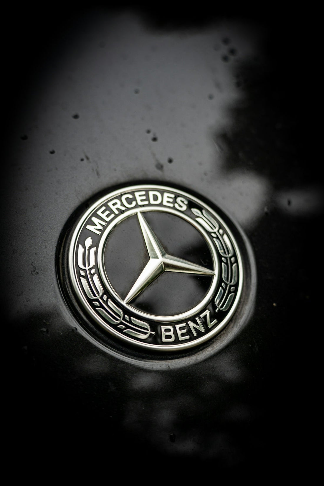 Close-up of Mercedes-Benz car badge with chrome logo on glossy black surface