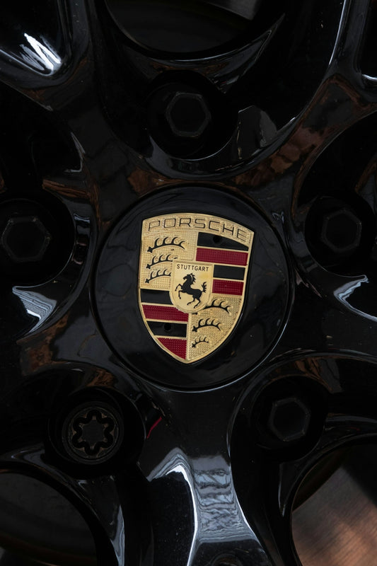 Close-up of a Porsche wheel center cap with gold crest and black alloy rim