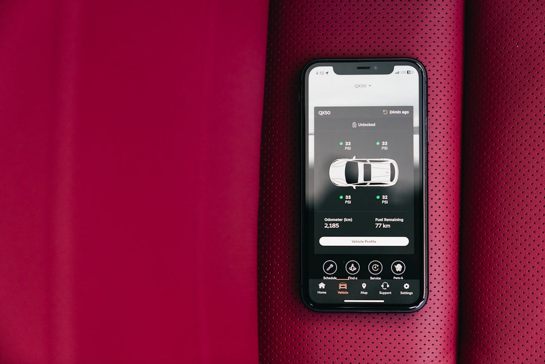 Smartphone displaying car diagnostic app on perforated red leather car seat
