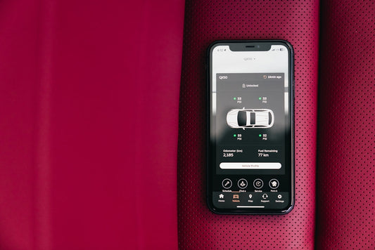Smartphone displaying car diagnostic app on perforated red leather car seat