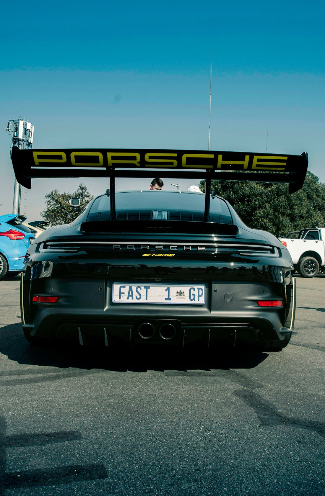 Rear view of black Porsche GT3 RS with large spoiler, custom plate, parked outdoors
