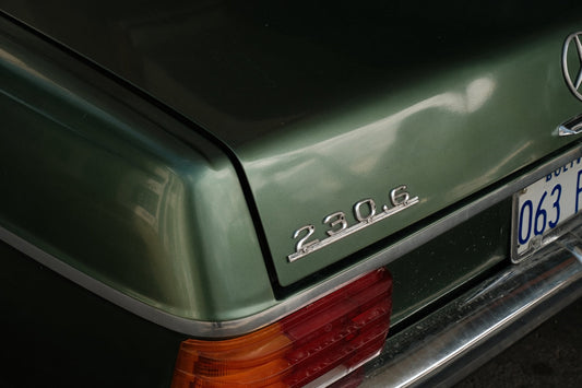 Close-up of a classic green Mercedes-Benz 230.6 rear badge and taillight with license plate