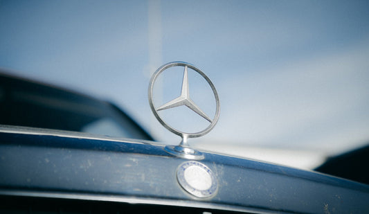 Mercedes-Benz hood ornament on a luxury car with blue sky background
