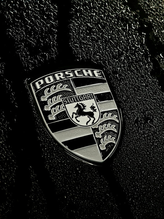 Porsche car badge with raindrops on black paint, luxury sports car detail