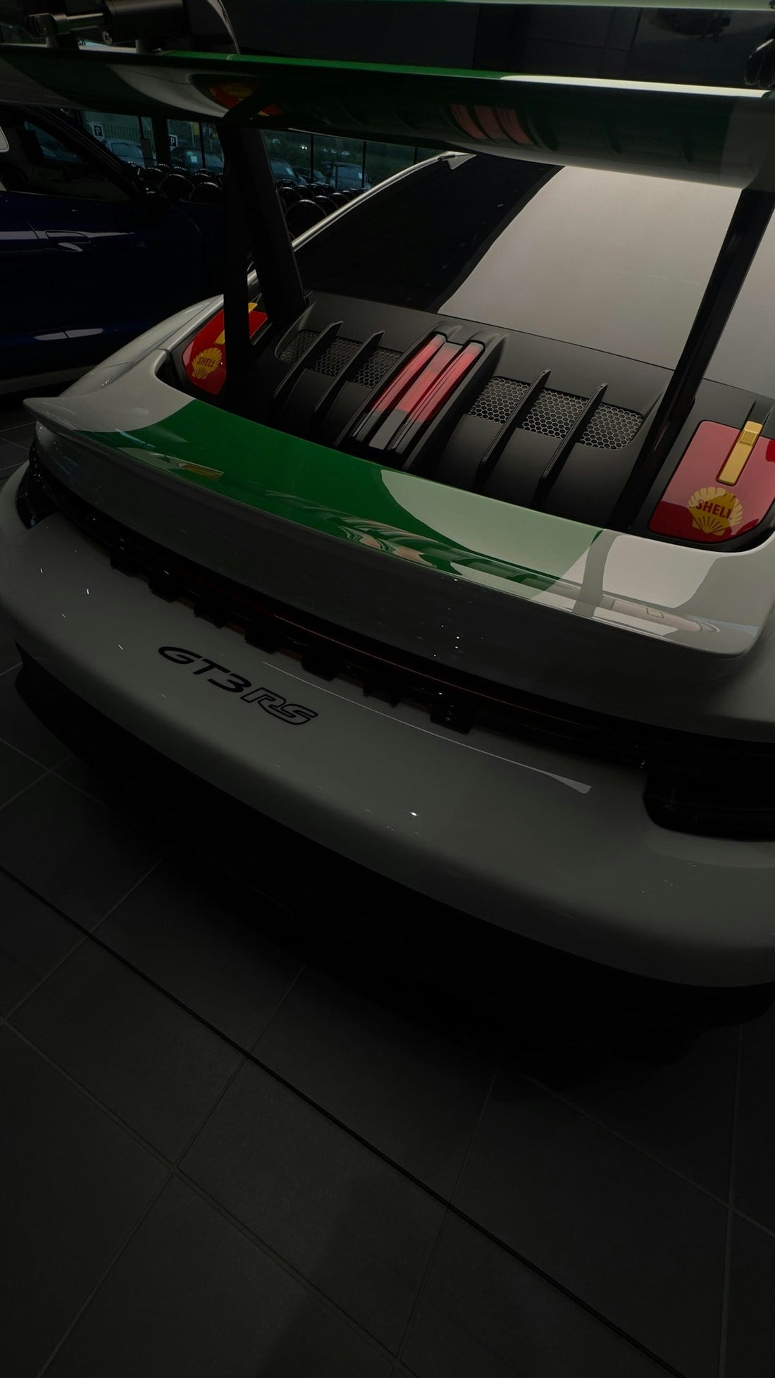 Rear view of a white Porsche GT3 RS with a large rear wing in a showroom