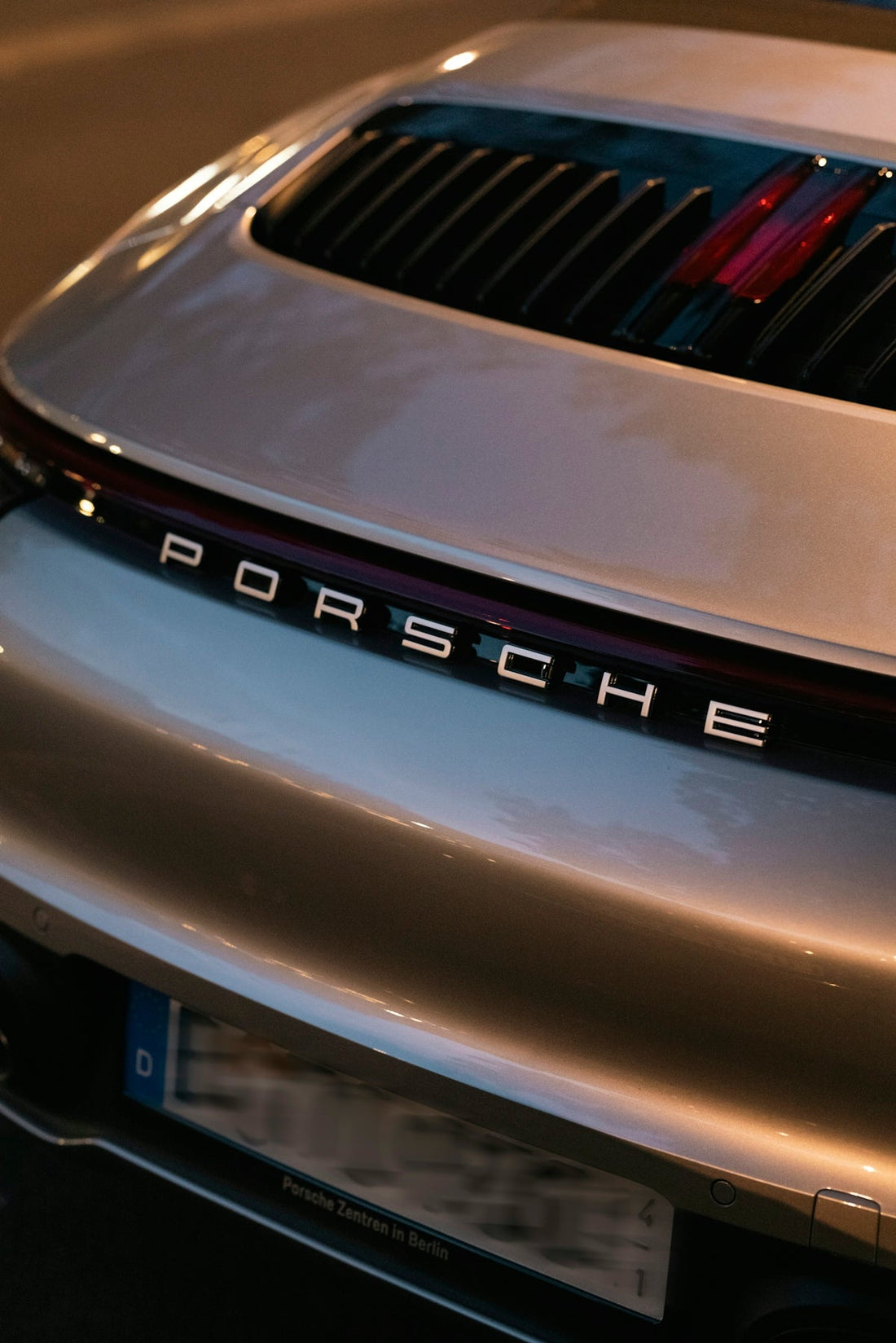 Rear view of a silver Porsche sports car with prominent badging and sleek tail design