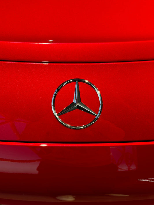 Chrome Mercedes-Benz emblem on shiny red supercar rear