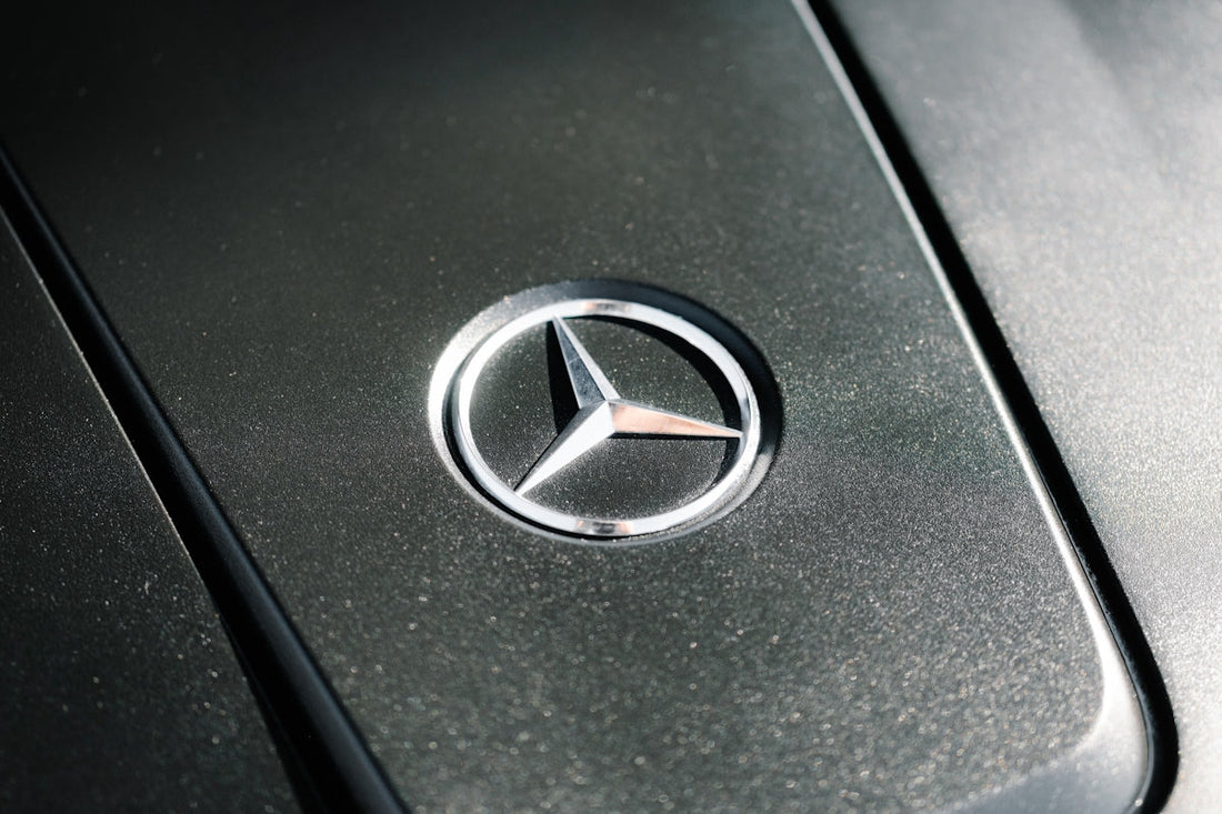 Close-up of a Mercedes-Benz hood emblem on a metallic car surface, luxury car detail