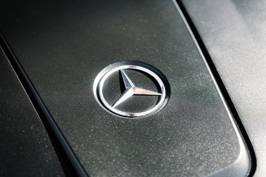 Close-up of a Mercedes-Benz hood emblem on a metallic car surface, luxury car detail