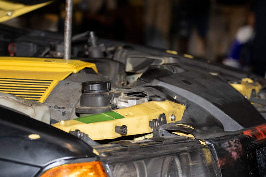 Close-up of exotic car engine bay with yellow accents and diagnostic access points