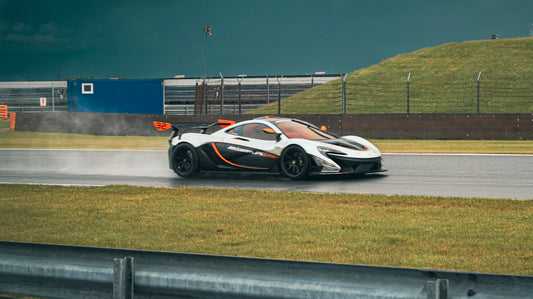 White mclaren p1 racing on a wet track.