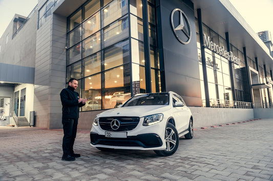 Man standing by a white mercedes-benz suv outside dealership.