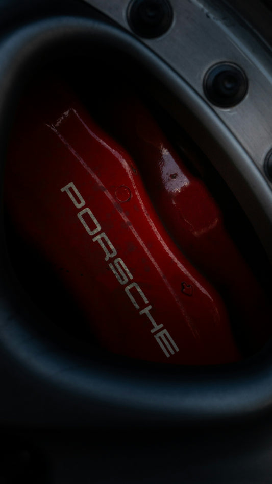 Red porsche brake caliper visible on a car wheel.